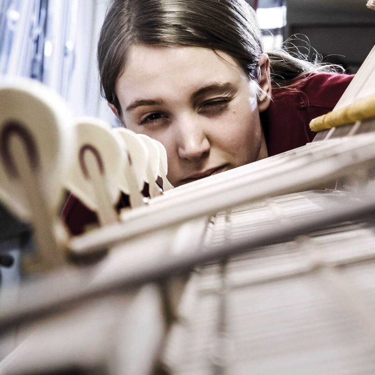 Craftswoman looking at the hammers inside the piano